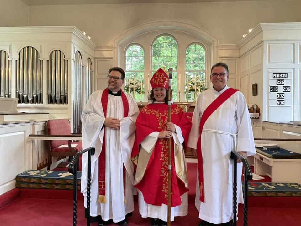 Clergy and bishop at All Hallows Parish church interior.
